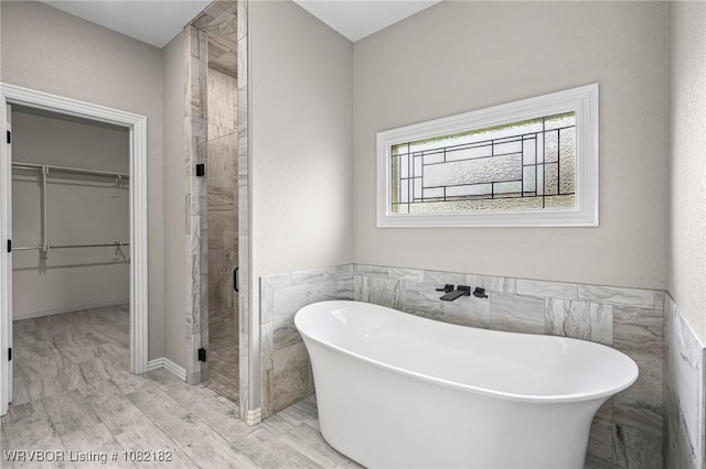 9505 Harmony Ridge Rd, Fort Smith, AR 72916 - full bath featuring a walk in closet, a shower stall, a freestanding bath, tile walls, and a wainscoted wall