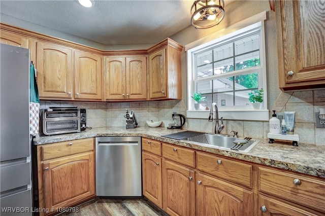 kitchen with a toaster, a sink, decorative backsplash, wood finished floors, and appliances with stainless steel finishes