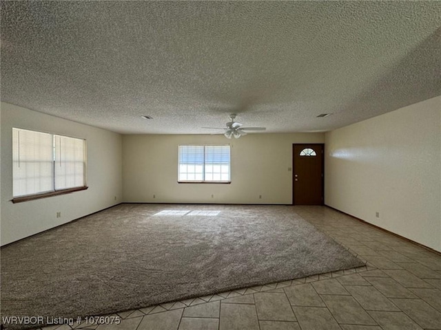 carpeted spare room with ceiling fan and a textured ceiling