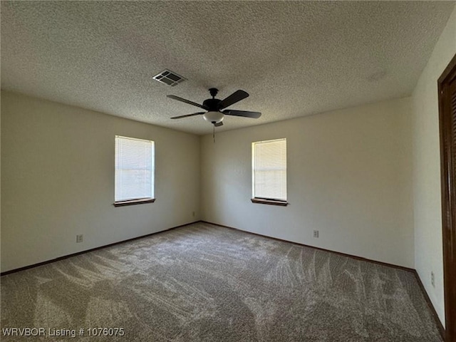 empty room with carpet flooring, ceiling fan, and a textured ceiling