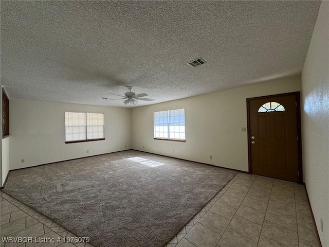 entrance foyer featuring ceiling fan, light colored carpet, and a textured ceiling