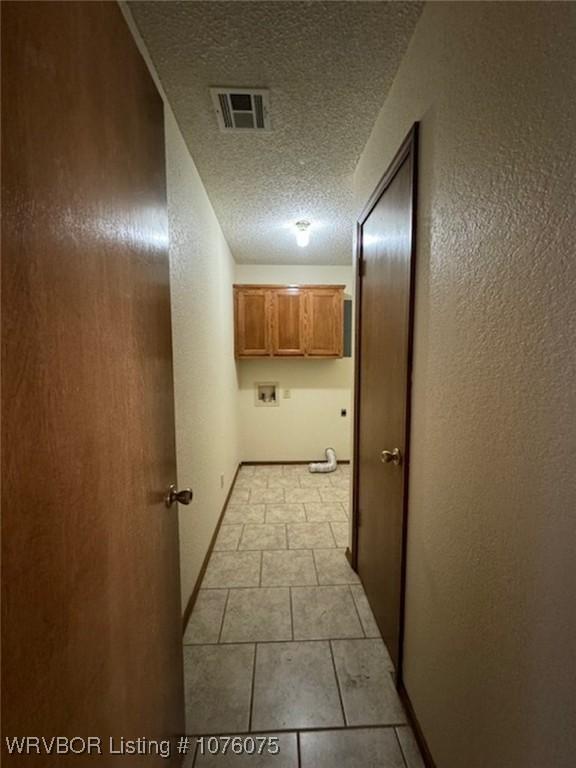 corridor with a textured ceiling and light tile patterned flooring