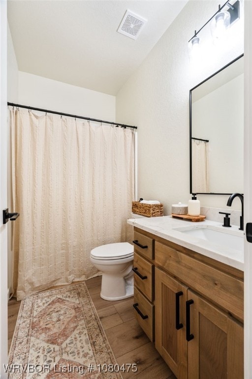 1905 Barnes St, Pocola, OK 74902 - bathroom featuring lofted ceiling, visible vents, toilet, wood finished floors, and vanity