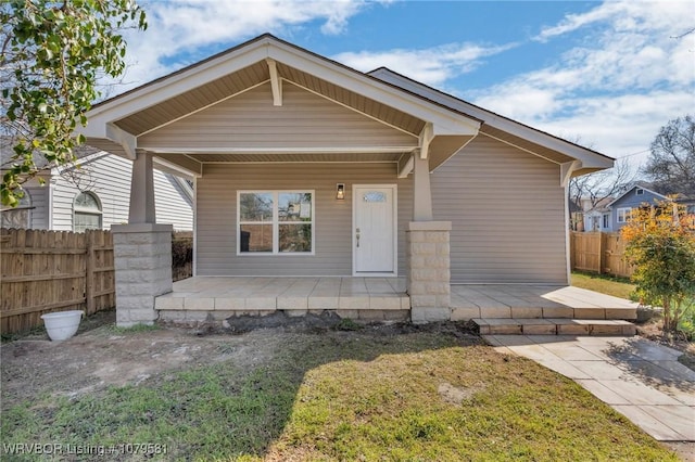 view of front of home featuring a front lawn, fence, and covered porch