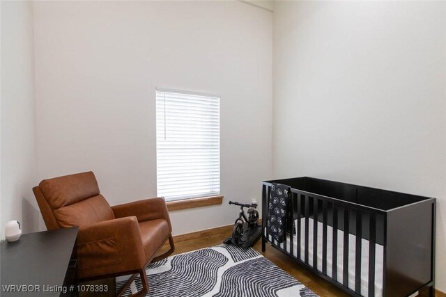 bedroom with dark hardwood / wood-style floors and a nursery area