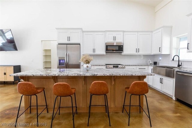 kitchen with light stone countertops, stainless steel appliances, sink, and a center island