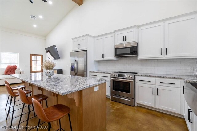 kitchen featuring stainless steel appliances, backsplash, white cabinets, and a center island