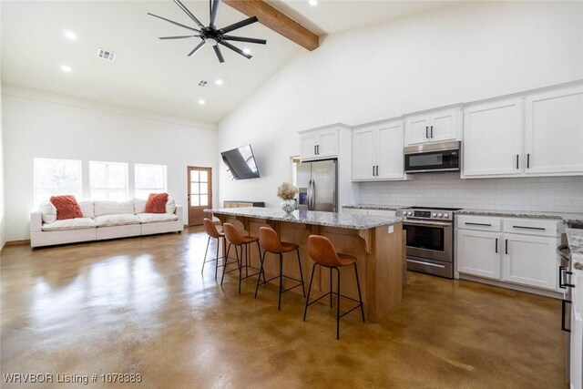 kitchen with a breakfast bar area, stainless steel appliances, white cabinets, and a center island