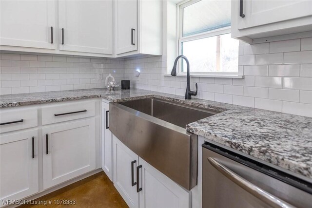 kitchen featuring light stone counters, white cabinetry, and stainless steel dishwasher