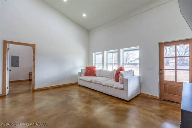 living room featuring concrete floors, electric panel, and high vaulted ceiling