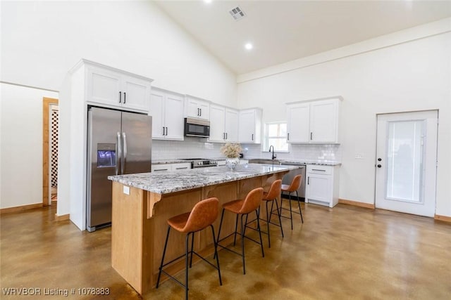 kitchen featuring high vaulted ceiling, appliances with stainless steel finishes, white cabinetry, and a center island