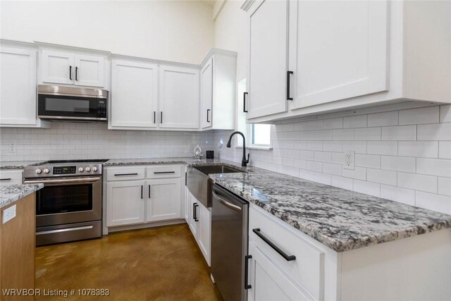 kitchen with backsplash, white cabinetry, and stainless steel appliances