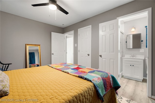 bedroom featuring connected bathroom, a sink, light wood-style flooring, and ceiling fan