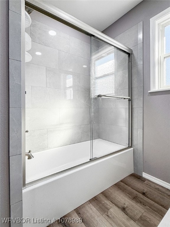 full bath with enclosed tub / shower combo, wood finished floors, and baseboards