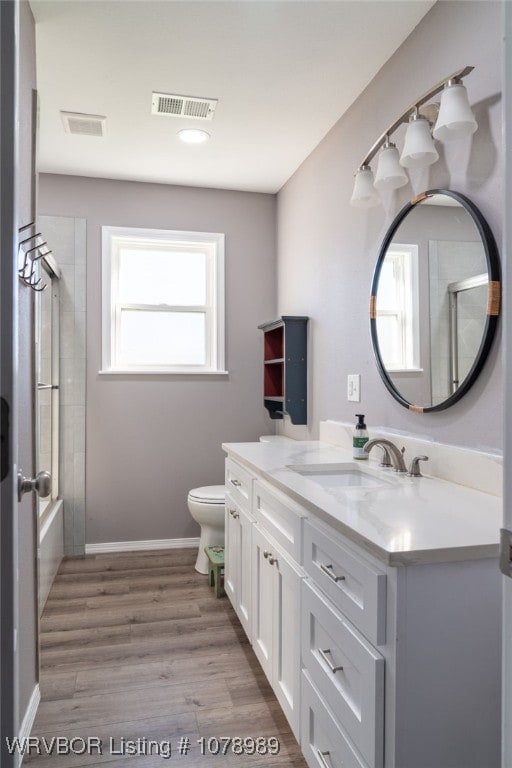 full bathroom featuring toilet, wood finished floors, vanity, and visible vents