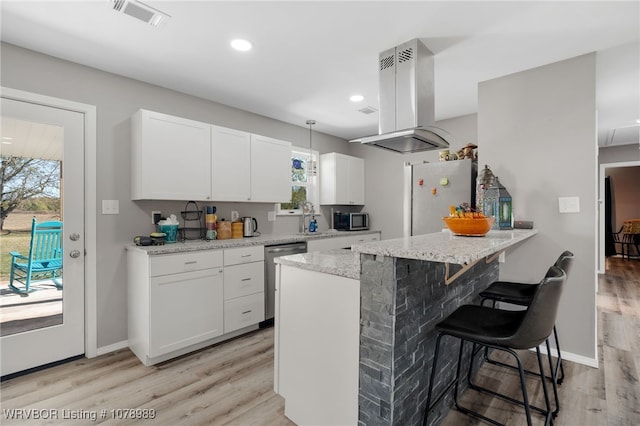 kitchen with visible vents, island range hood, white cabinets, a peninsula, and stainless steel appliances