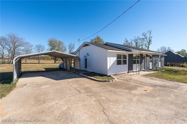 view of front of house featuring a front yard, concrete driveway, and a detached carport