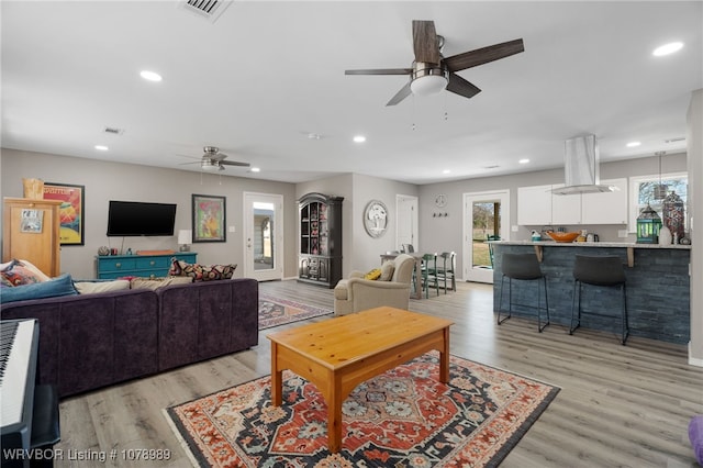 living room with recessed lighting, visible vents, and light wood finished floors