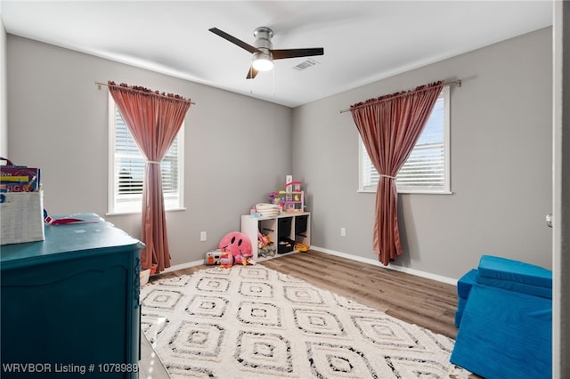 bedroom featuring a ceiling fan, baseboards, visible vents, and wood finished floors