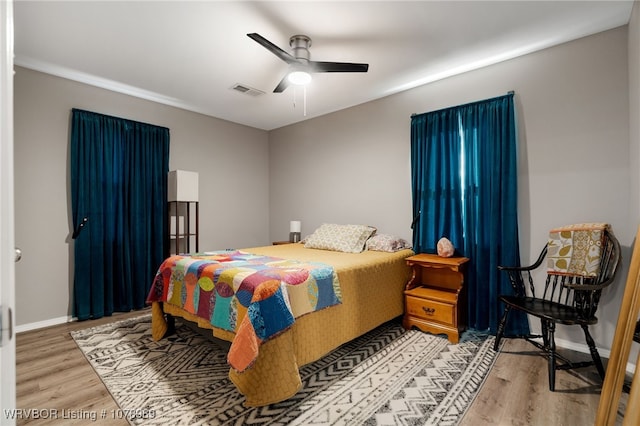 bedroom featuring baseboards, a ceiling fan, visible vents, and light wood-style floors