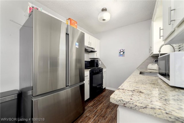 128 Saskatchewan Rd, Roland, OK 74954 - kitchen featuring freestanding refrigerator, black gas range oven, under cabinet range hood, dark wood finished floors, and white cabinetry