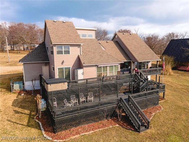 back of property with a yard, a hot tub, and a deck