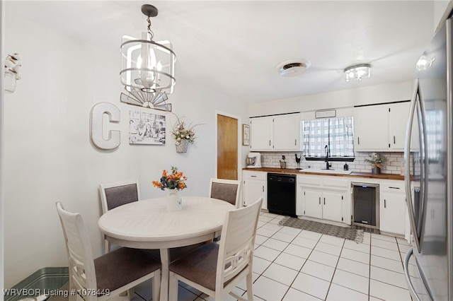 kitchen with black dishwasher, white cabinets, hanging light fixtures, and stainless steel refrigerator