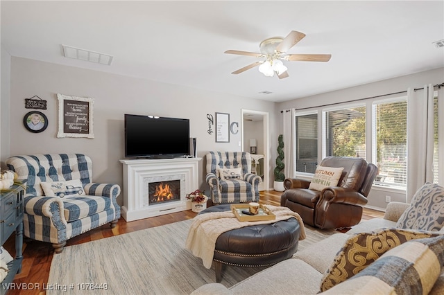 living room featuring ceiling fan, wood-type flooring, and a premium fireplace