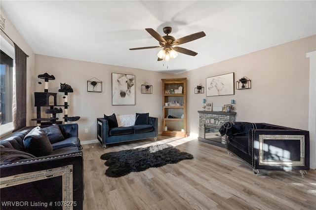 living room with a fireplace, wood-type flooring, and ceiling fan