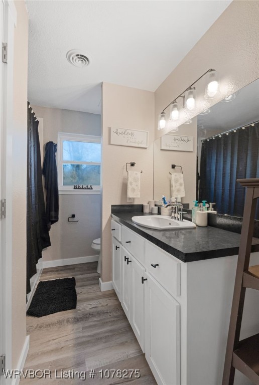 bathroom featuring toilet, vanity, and hardwood / wood-style flooring