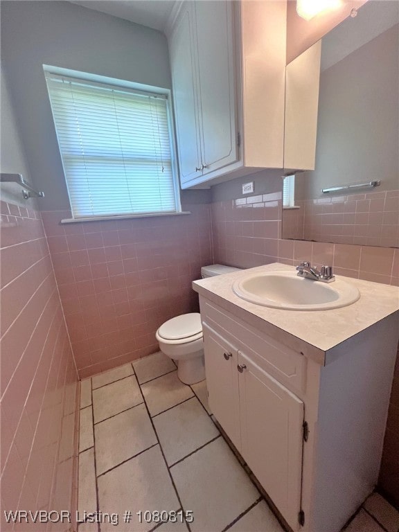 half bath with tile patterned flooring, tile walls, toilet, and vanity