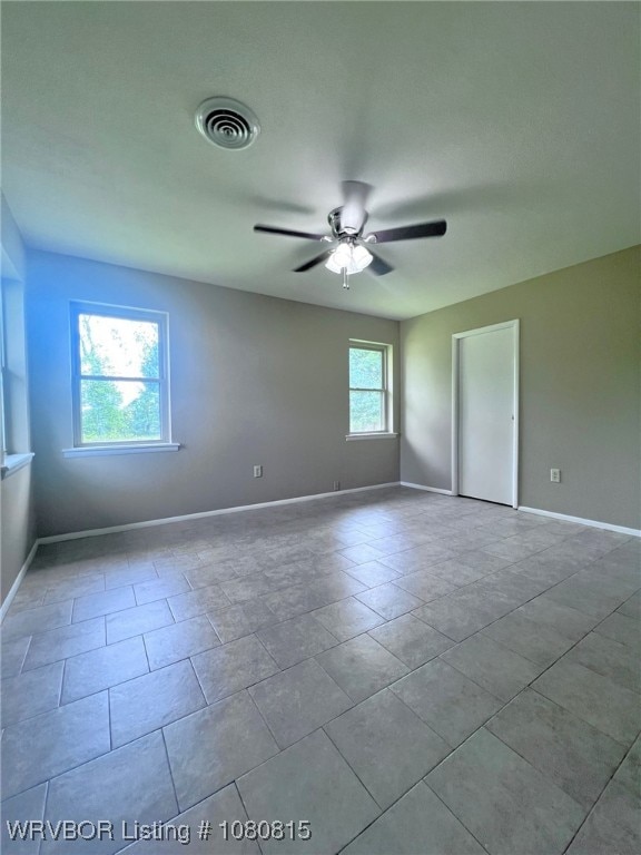 unfurnished room featuring baseboards, a ceiling fan, and visible vents