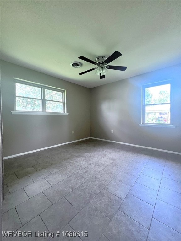 tiled spare room with baseboards, a ceiling fan, and visible vents
