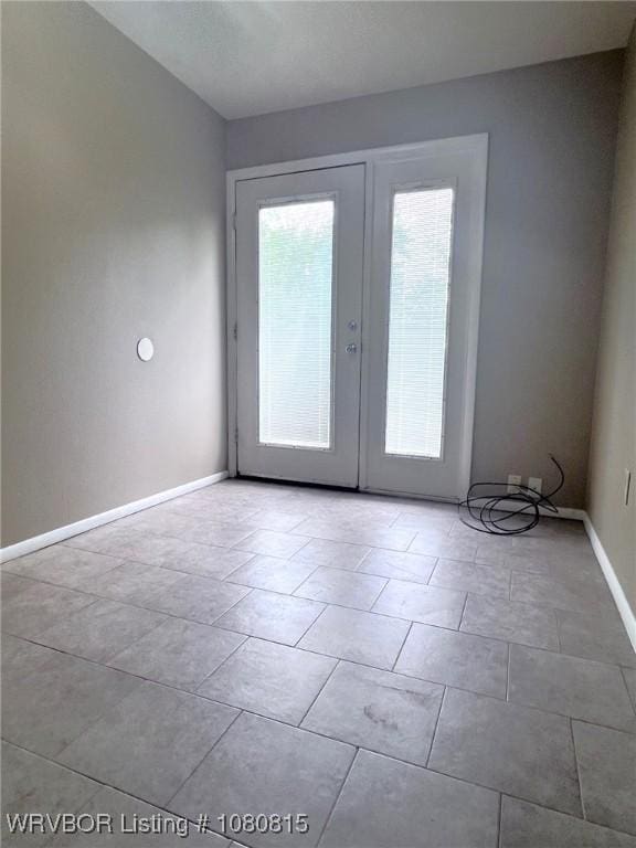 empty room with baseboards and french doors