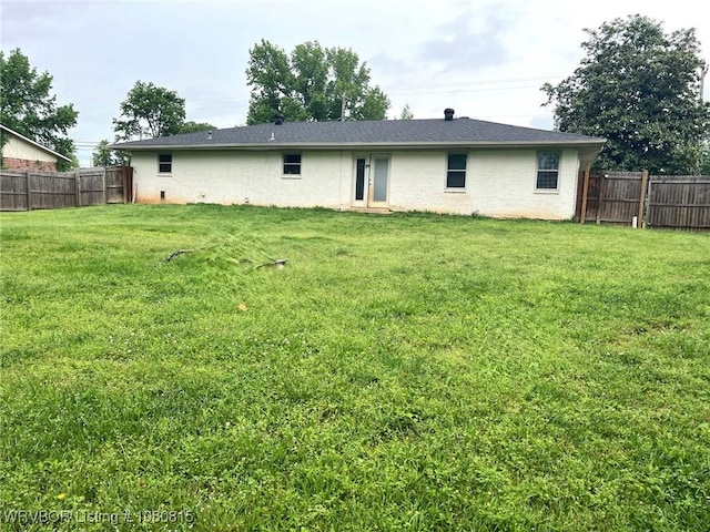 back of house featuring a yard and fence