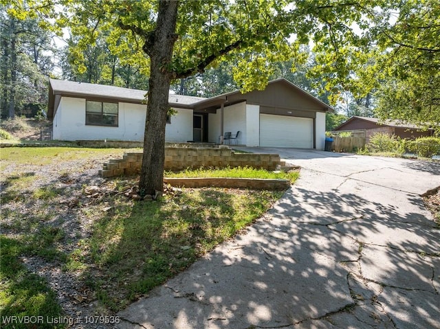 single story home featuring an attached garage, concrete driveway, and fence