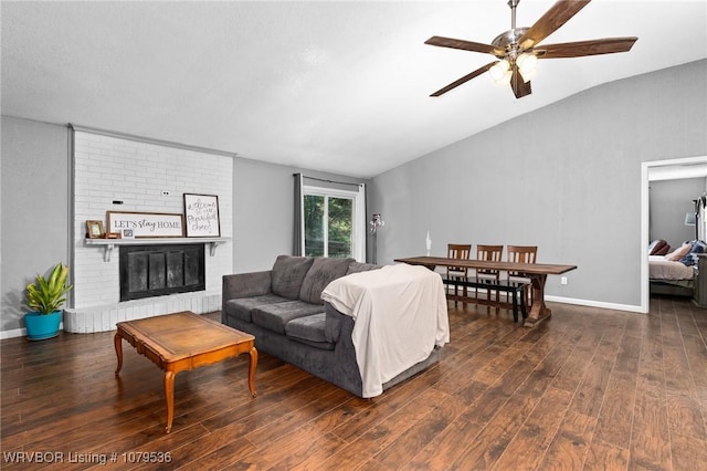 living room featuring baseboards, lofted ceiling, a brick fireplace, and hardwood / wood-style floors