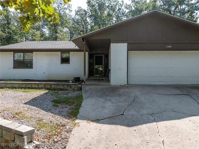 ranch-style house with a garage, brick siding, and concrete driveway