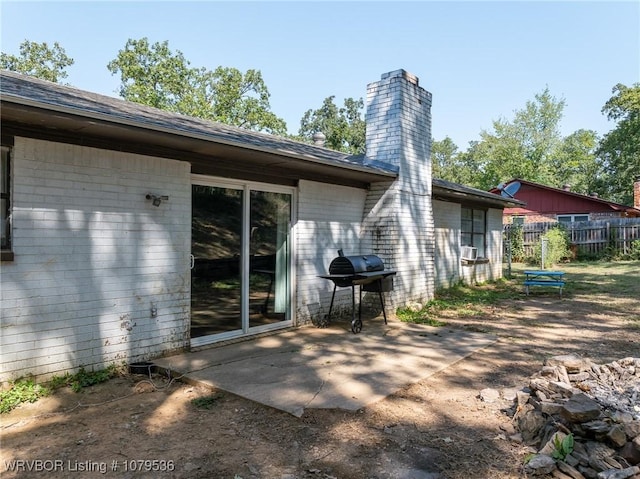 back of property with a chimney, a patio, and fence