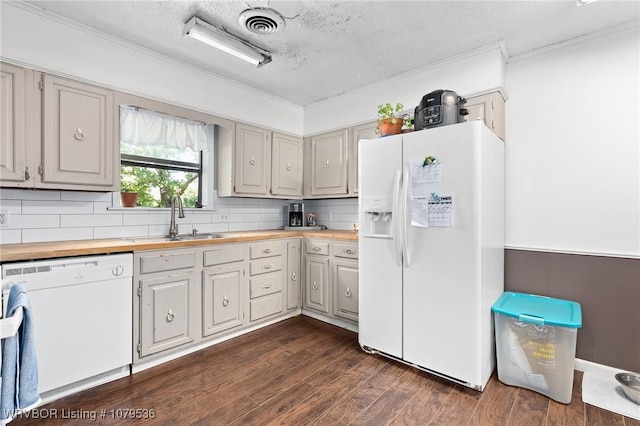 kitchen with visible vents, dark wood-type flooring, butcher block countertops, white appliances, and a sink