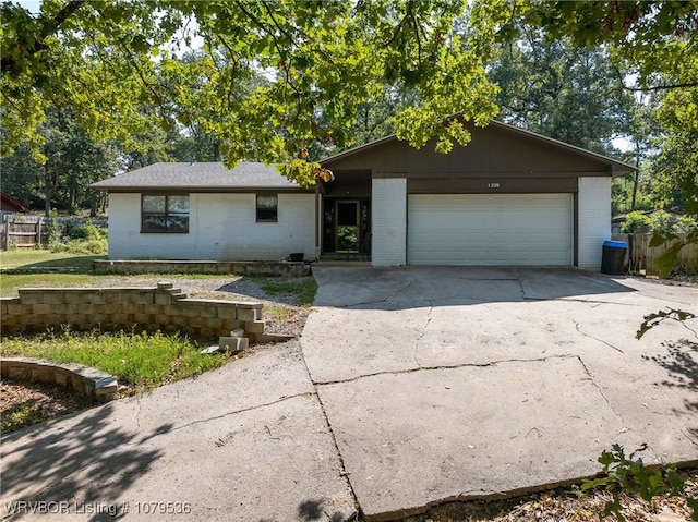 single story home featuring brick siding, an attached garage, and driveway