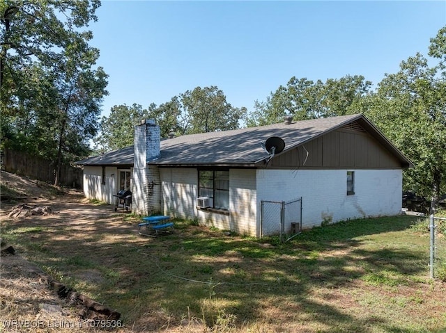 rear view of property with brick siding, fence, a lawn, cooling unit, and a chimney