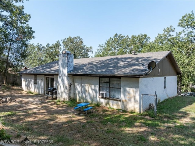 rear view of property with cooling unit, a lawn, brick siding, and a chimney