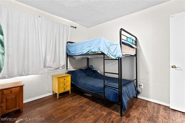 bedroom featuring baseboards, a textured ceiling, and wood finished floors