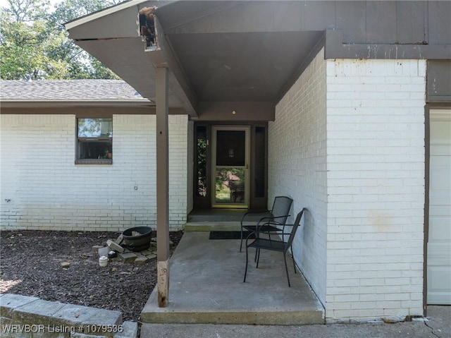 entrance to property with brick siding and roof with shingles