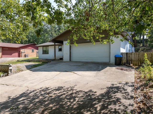 view of front facade featuring brick siding, driveway, a garage, and fence