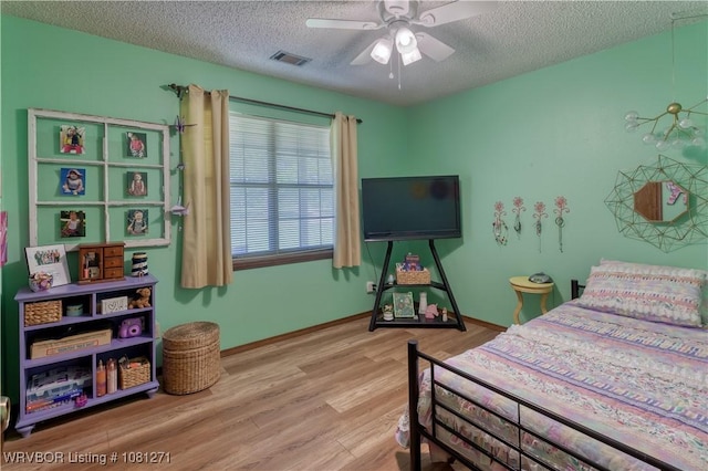 3001 Coral Cir, Alma, AR 72921 - bedroom featuring a textured ceiling, wood finished floors, baseboards, and a ceiling fan