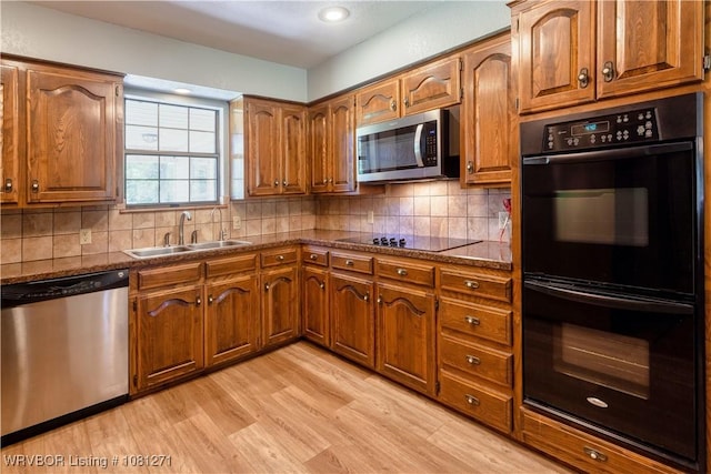 3001 Coral Cir, Alma, AR 72921 - kitchen featuring black appliances, a sink, light wood-type flooring, brown cabinetry, and decorative backsplash
