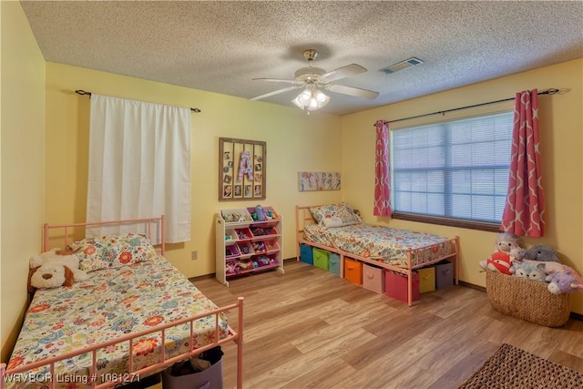 3001 Coral Cir, Alma, AR 72921 - bedroom featuring light wood-style flooring, a textured ceiling, a ceiling fan, and baseboards