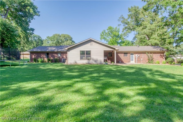 3001 Coral Cir, Alma, AR 72921 - back of house featuring a trampoline, brick siding, and a yard